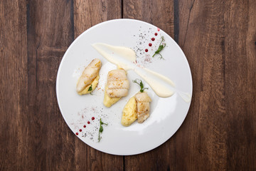 Halibut fillet with potato cream and cauliflower sauce. On a wooden table.