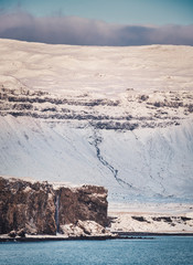 coast of the atlantic ocean with a huge mountain in the snow and a cliff