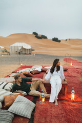 Stylish european couple in love enjoying evening together in luxury glamping camp in Sahara desert, Morocco. Romantic mood, lying on multicolor pillows. - 331928423