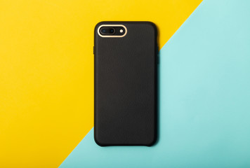 Black blank leather smartphone case on yellow half blue background.