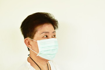 Asian elder woman wearing hygienic mask robe for protection nose and mouth from virus