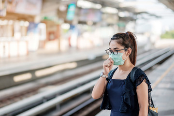 young Asian woman wearing Surgical face mask against Novel coronavirus or Corona Virus Disease (Covid-19) at public train station. Hygiene, Healthcare and infection concept