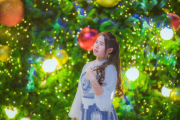 Beautiful girl with Christmas tree and bokeh