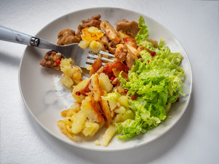 Breakfast with fried chicken and potatoes with a slide of finely chopped Beijing cabbage on a gray plate