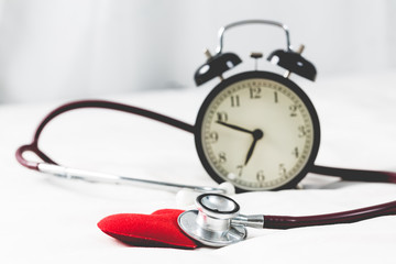 red heart with stethoscope and alarm clock close up