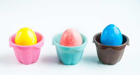 colorful Easter eggs in colored cupcake molds on a white background