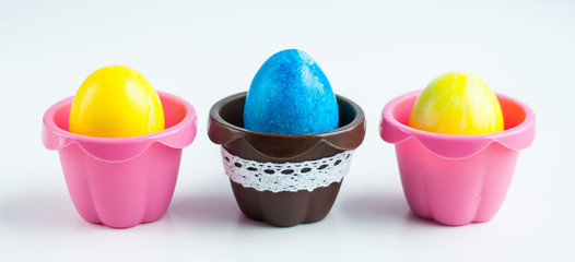 colorful Easter eggs in colored cupcake molds on a white background. Symmetrical image