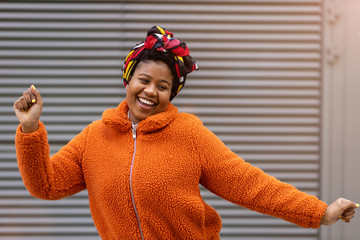 Happy young woman dancing in front of a wall
