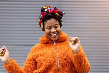 Happy young woman dancing in front of a wall