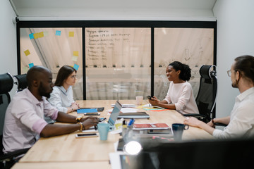 Black happy woman working on project with colleagues in office space