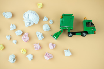 Miniature of crumpled office paper and miniature green plastic garbage truck