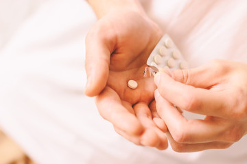 Closeup of man hands with plate of white round pills. Sick man taking oral medications for treatment coronavirus COVID-19 symptoms. Drug addiction. Man taking vitamins or painkillers. Pills in hand