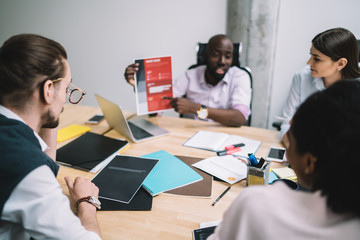 Adult multiracial business people discussing reports during conference in office