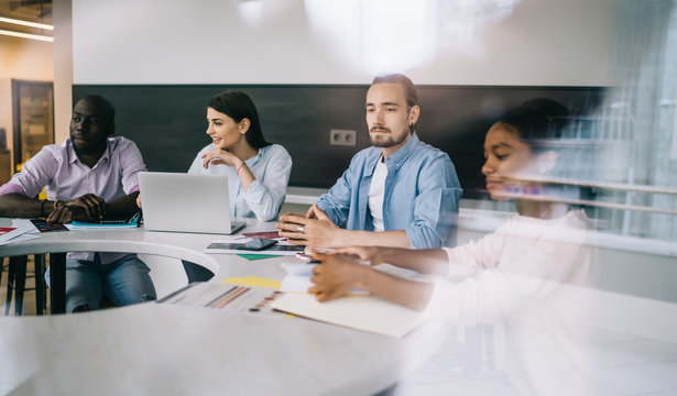 Multiracial coworkers sitting at table on office