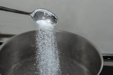 Salz vom Löffel in das kochende Wasser schütten