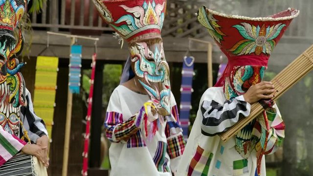 The  people in Thailand on phitakhon ghost festival holiday carnival wearing colorful custume clothes wearing hand paint mask dancing on street with happiness.  