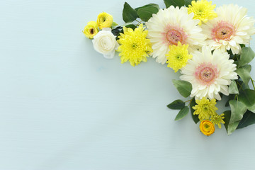 spring bouquet of yellow and white gerbera flowers over pastel wooden background. top view, flat lay