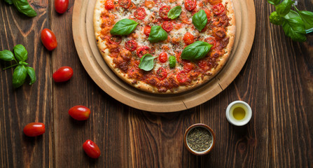 Delicious margherita pizza with tomatoes and basil on wood.