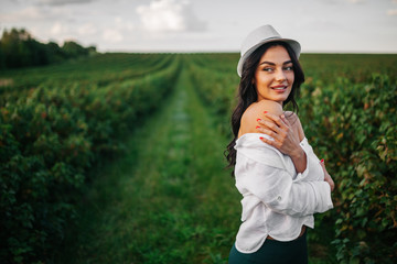 Beautiful romantic young girl in light peasant dress and a hat enjoying a walk around the tea...