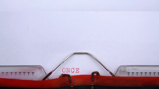 Once upon a time - phrase printed on an old typewriter in red letters, close up. vintage inscription