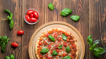 Delicious margherita pizza with tomatoes and basil on wood.