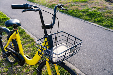 Fototapeta na wymiar Yellow bike on green grass. Rental transport. Bicycle basket.