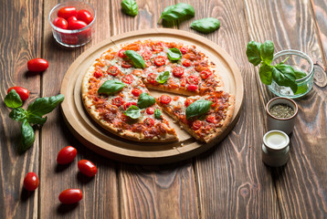 Delicious margherita pizza with tomatoes and basil on wood.