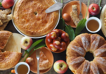 Easter background with homemade cakes and colored eggs. Treat on a wooden table with Easter cakes, pies, eggs, apples.Top view.
