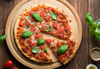 Delicious margherita pizza with tomatoes and basil on wood.