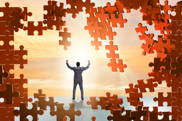 Businessman breaking the wall of jigsaw puzzle