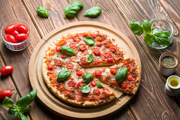 Delicious margherita pizza with tomatoes and basil on wood.
