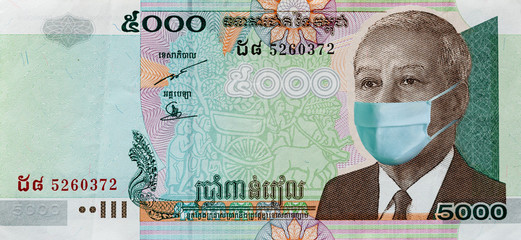 Coronavirus in Cambodia. Quarantine and global recession. 2000 Riel banknote with a face mask...