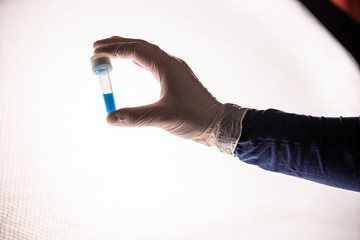 nurse in white surgical gloves holds test tube with coronavirus vaccine to stop the pandemic that has been spreading around the world since February 2020