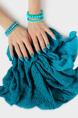 Fashionable oval long nails with different shades of nail polish from light blue to turquoise. Creative manicure on female hands with bracelets and a scarf.