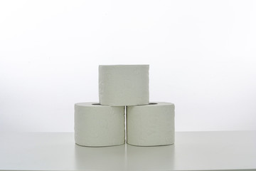 Drei Klopapierrollen zu einer Pyramide aufgebaut, weißer Hintergrund