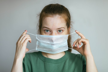 Woman puts on a protective medical mask. Prevention of infection and dissemination of coronavirus,...