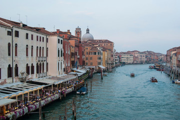 Twilight in Venice, Italy. View of the Grand Canal and houses on the shore, people ride boats.