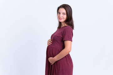 Profile view of young beautiful pregnant woman looking at camera