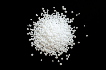 Urea fertilizer on a black background, top view. White mineral fertilizer balls - urea (carbamide)....