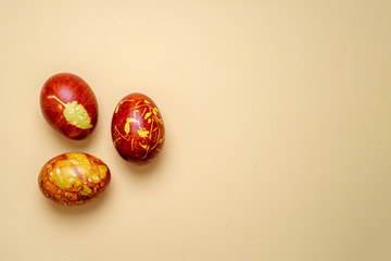 Obraz na płótnie Canvas Chicken eggs colored with old-fashioned natural method by onion husks isolated on light brown. Topview of brown eggs with different natural patterns with copyspace. Traditional Easter concept