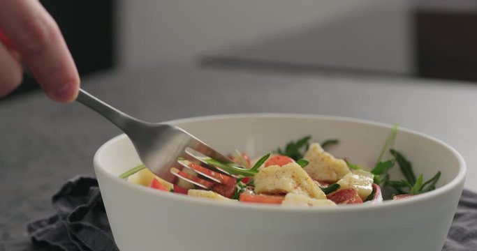 Slow motion man eat salad with cherry tomatoes, mixed grens and cheese from white bowl