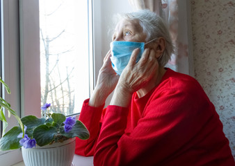 The Covid-19, health, safety and pandemic concept - senior old lonely woman sitting near the window