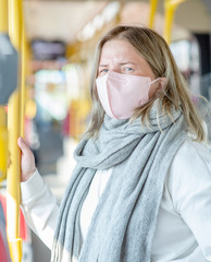 Woman wearing protective mask against virus and air pollution in th bus holding on to the handrail