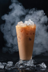 Iced Coffee wiht Milk in Tall Glass and Crushed Ice on Dark Background. Concept Refreshing Summer Drink