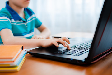 Distance learning online education. A schoolboy boy studies at home and does school homework. A...