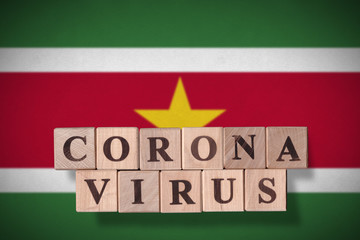 Flag of Suriname with wooden cubes spelling coronavirus on it. 2019 - 2020 Novel Coronavirus...