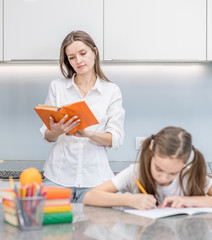 Mother helps daughter do schoolwork at home