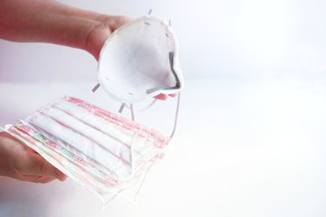 Close-up Hands of a senior woman holding a respirator and a medical protective mask. Coronavirus protection concept. Prevention options, isolation, quarantine, precautionary measures. Copy space.