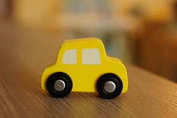 Closeup shot of a yellow wooden toy car on a wooden surface