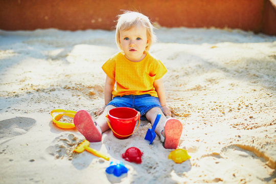 Adorable little girl having fun on playground in sandpit